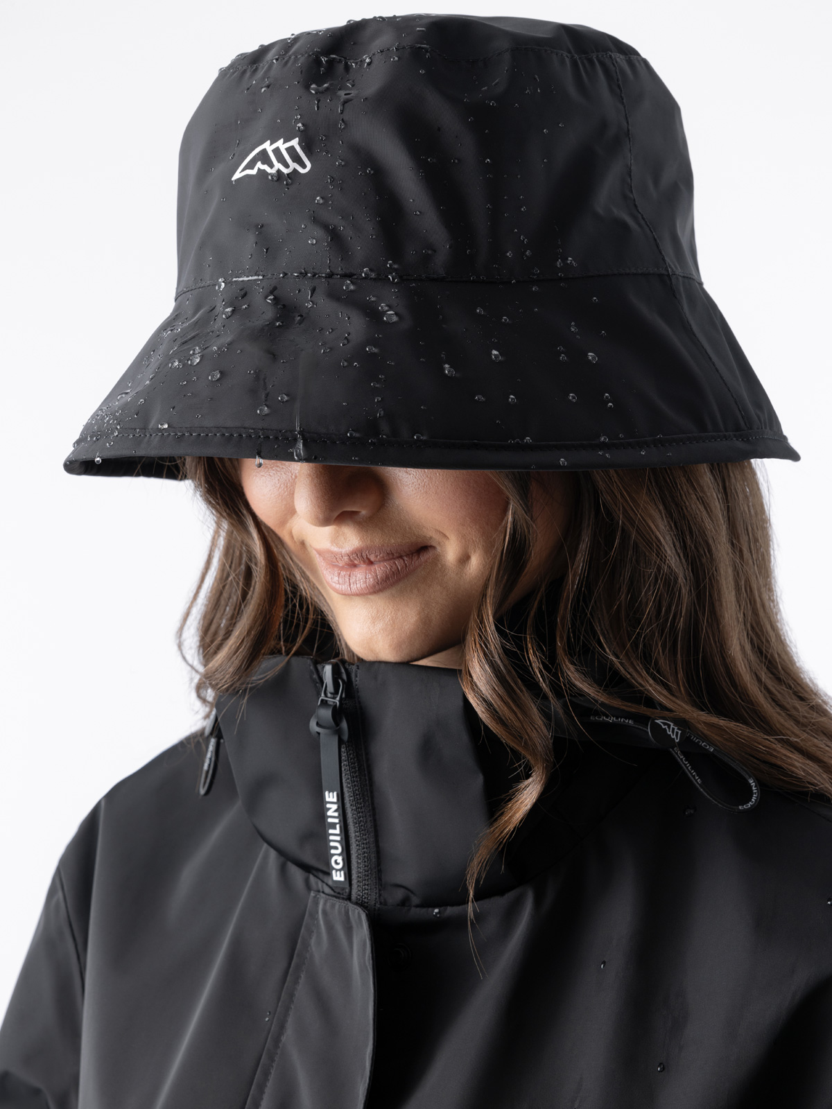 Equiline EQRAINS - Waterproof Rain Hat, in black, front view worn on female rider's head